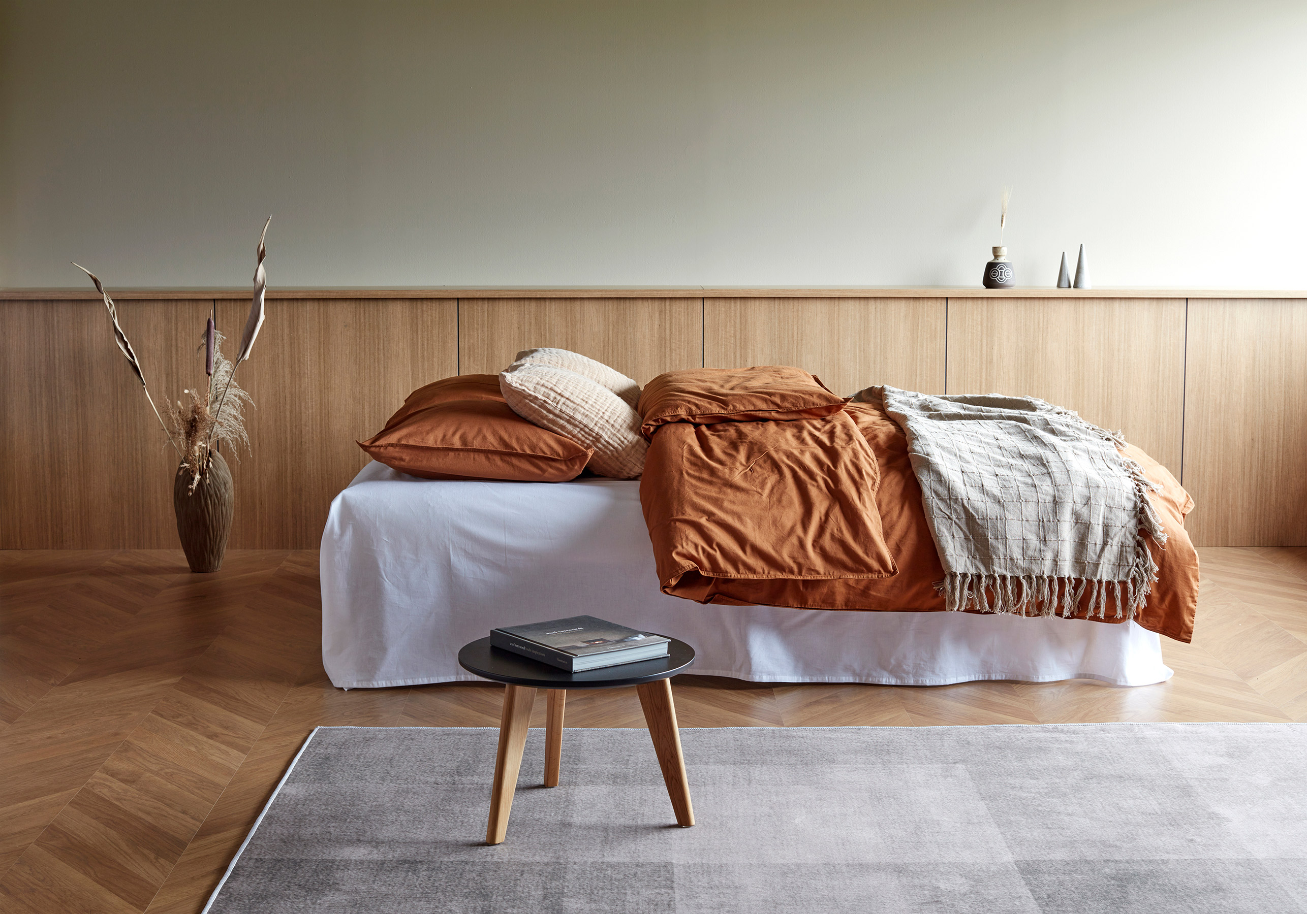 Aslak Bäddsoffa utbäddad med sängkläder i roströd och beige färg
