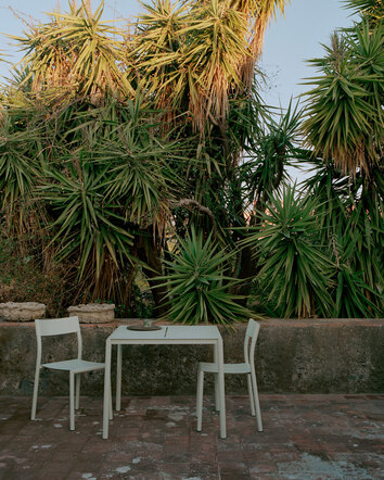 May Utebord och Utestol på solig terrass med palmer i bakgrunden
